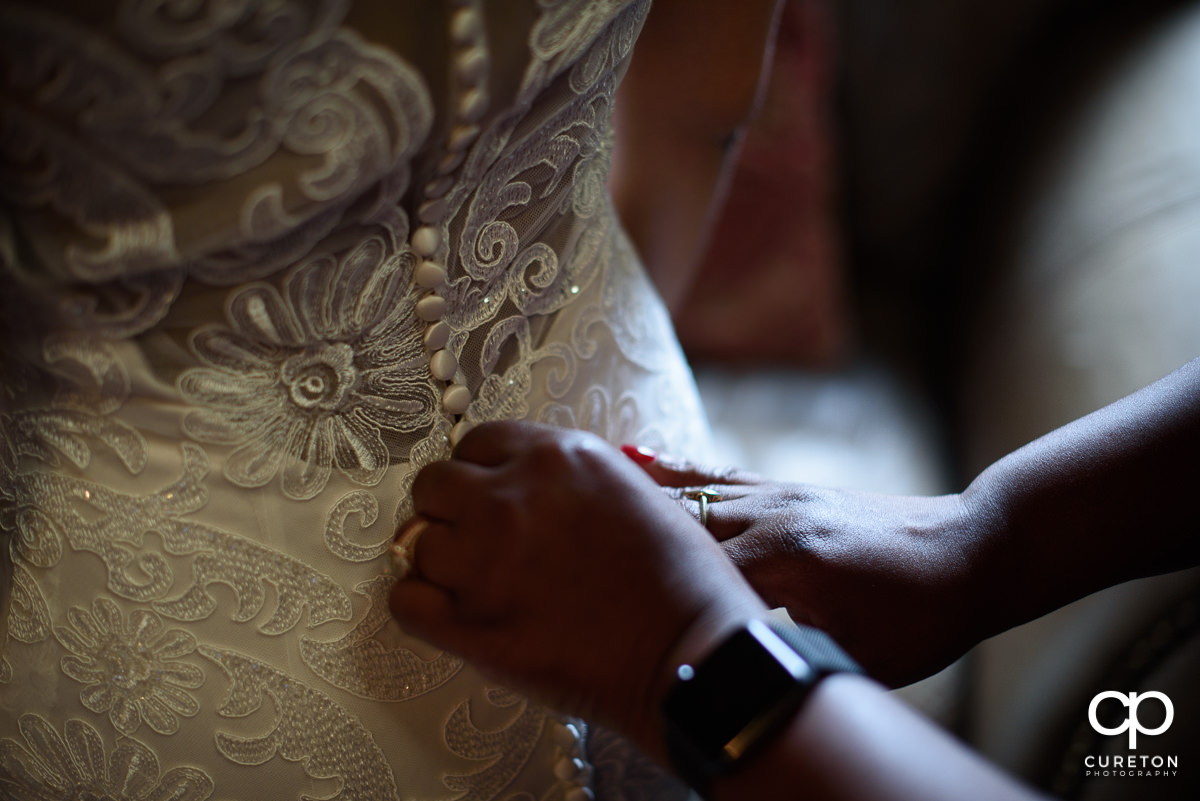Bride's mom's hands on the back of her dress.