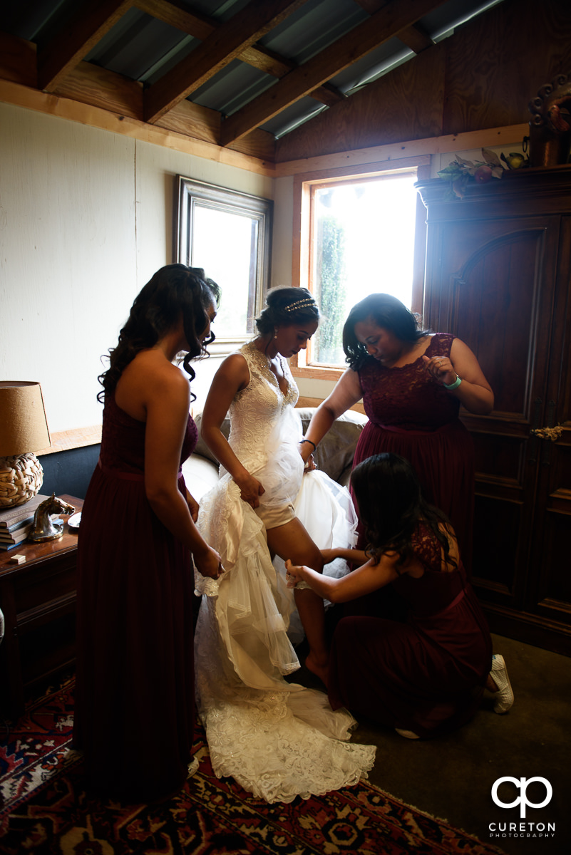 Bridesmaids helping the bride with her garter.