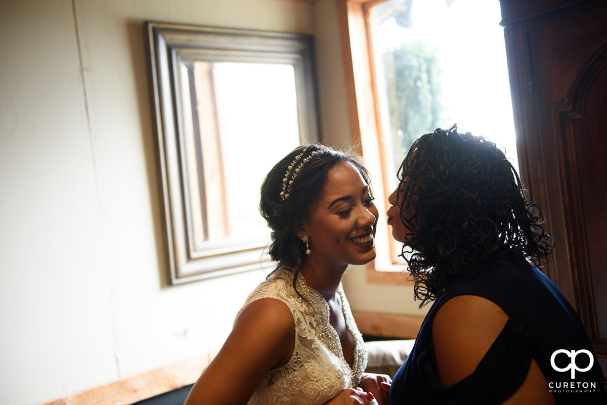 Bride's mom kissing her on the cheek.