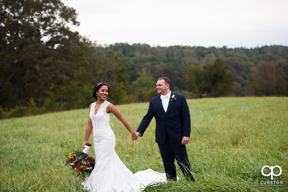 Bride and groom walking in a field at Lindsey Plantation.