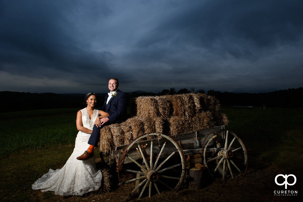 Bride and groom standing by an antique wagon.