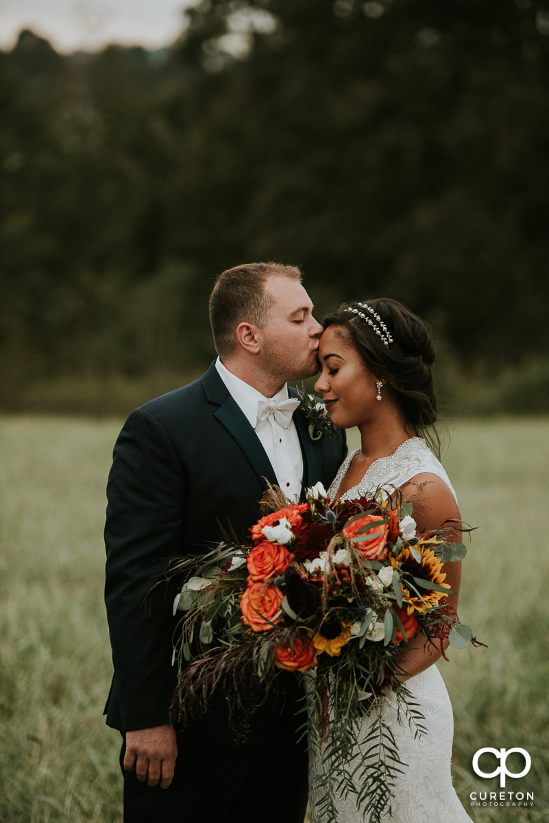 Groom kissing his bride on the forehead after the ceremony.