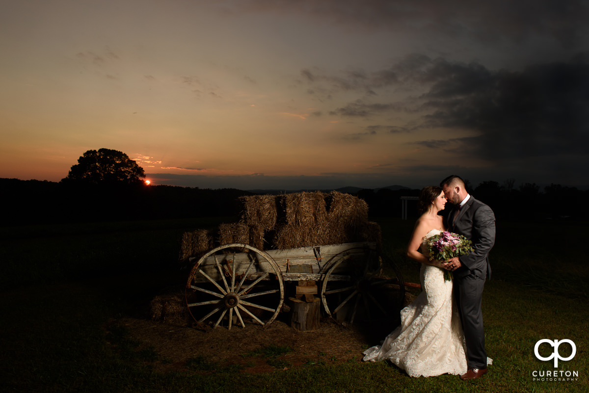 Bride and groom near the antique wagon in the field at Lindsey Plantation.