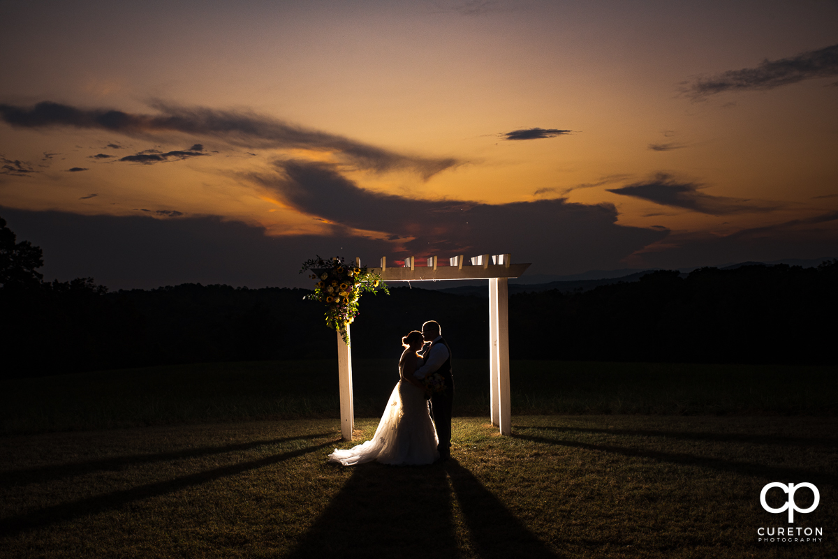 Groom kissing his bride at sunset underneath the arbor where they were married at their wedding at Lindsey Plantation in Taylors,SC.