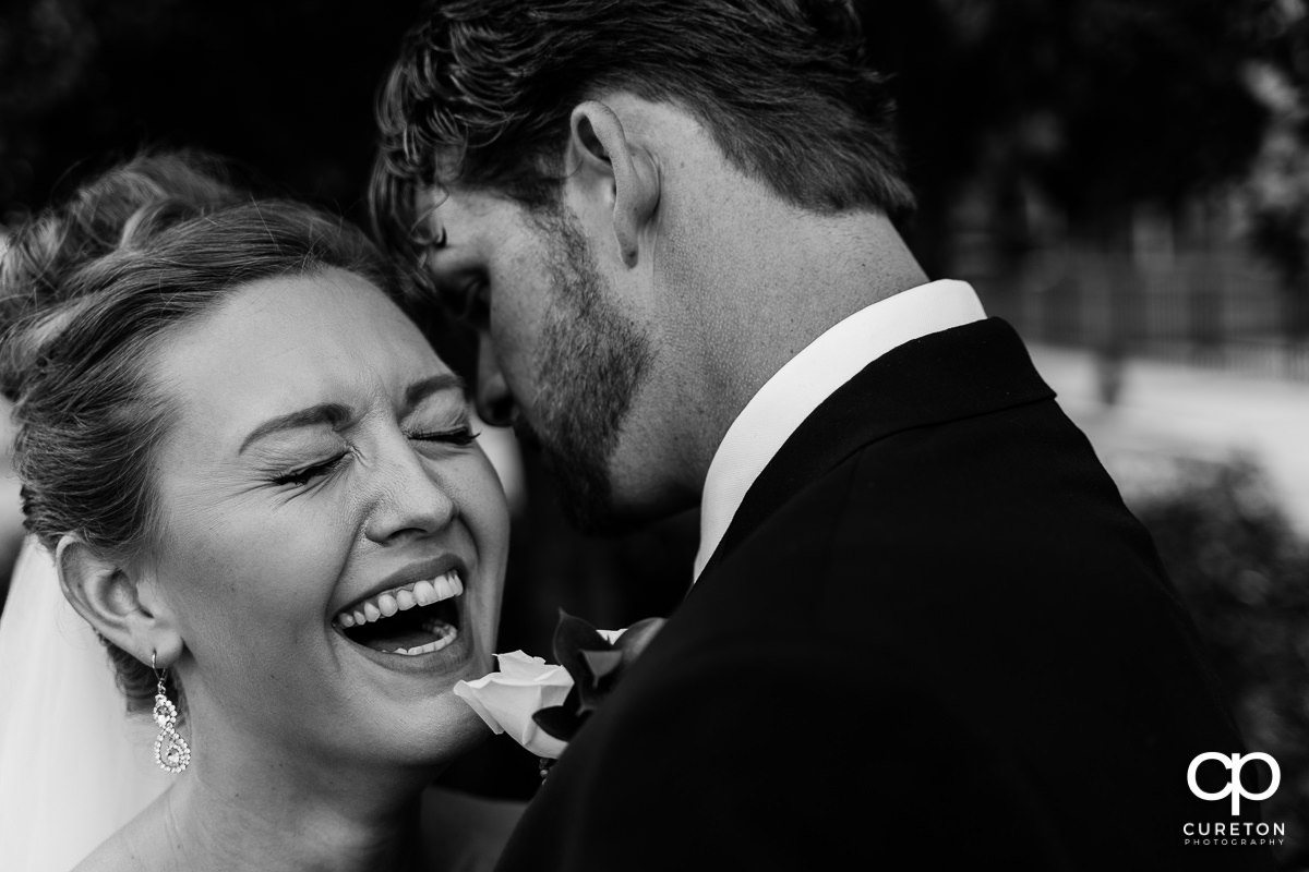 Bride laughing as her husband whispers into her ear after their Loft at Soby's wedding in downtown Greenville,SC.