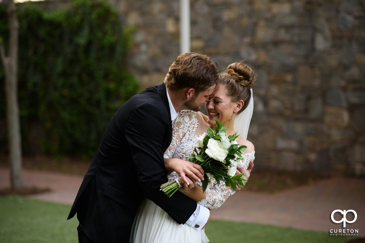 Groom holding his bride in the park after their wedding ceremony.