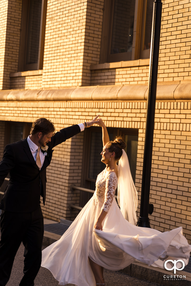 Bride and groom dancing in the sunlight on the streets on downtown Greenville SC after their wedding.