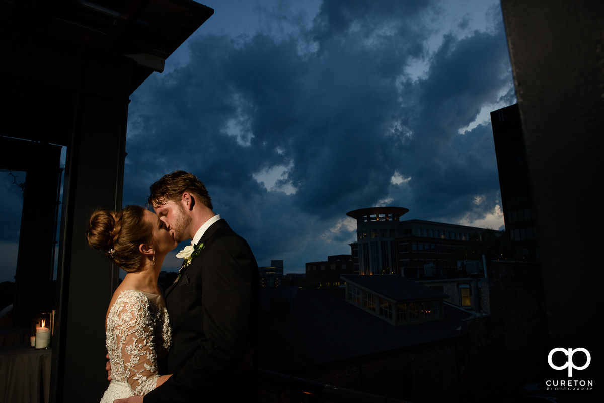 Groom kissing his bride at sunset on the rooftop at their Loft at Soby's wedding in downtown Greenville,SC.
