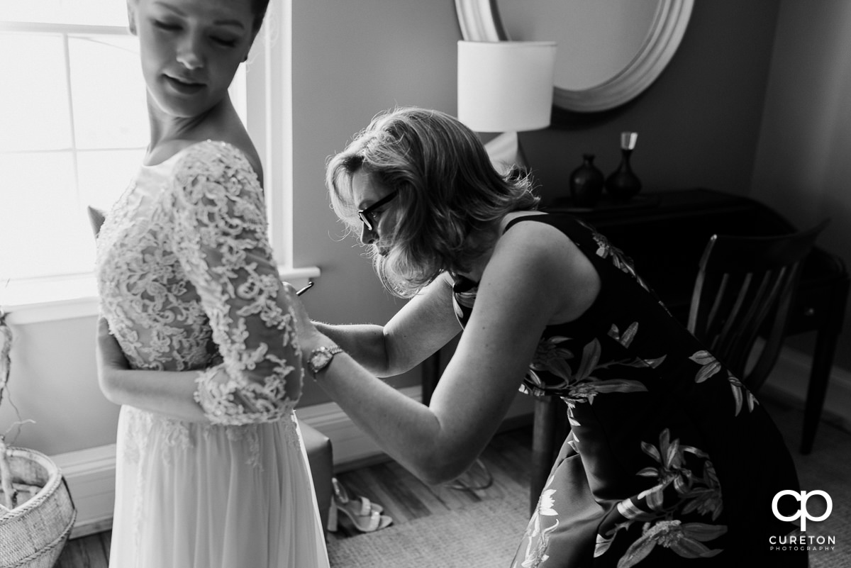 Bride's mother helping her into her dress.