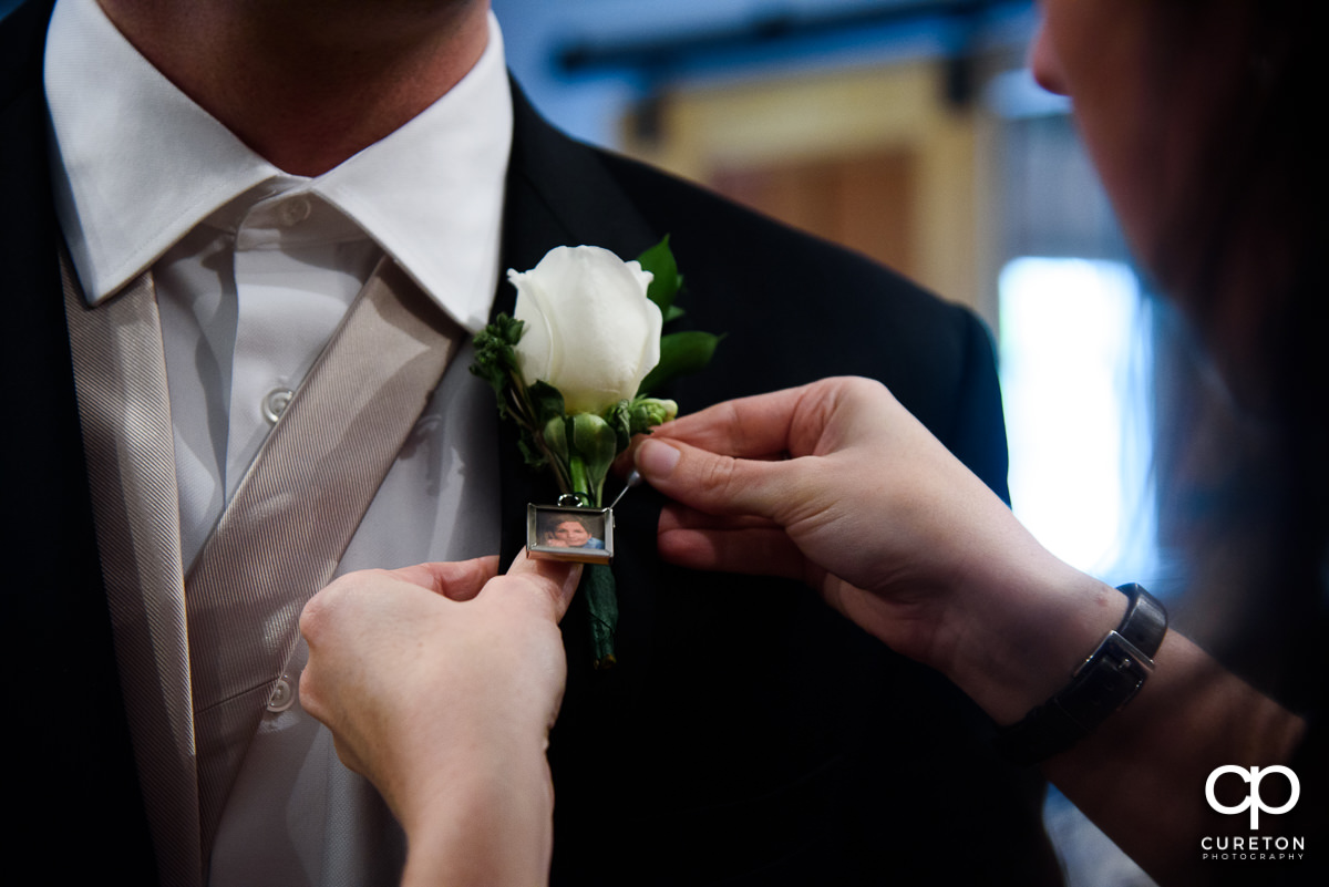 Groom pinning his boutonniere .