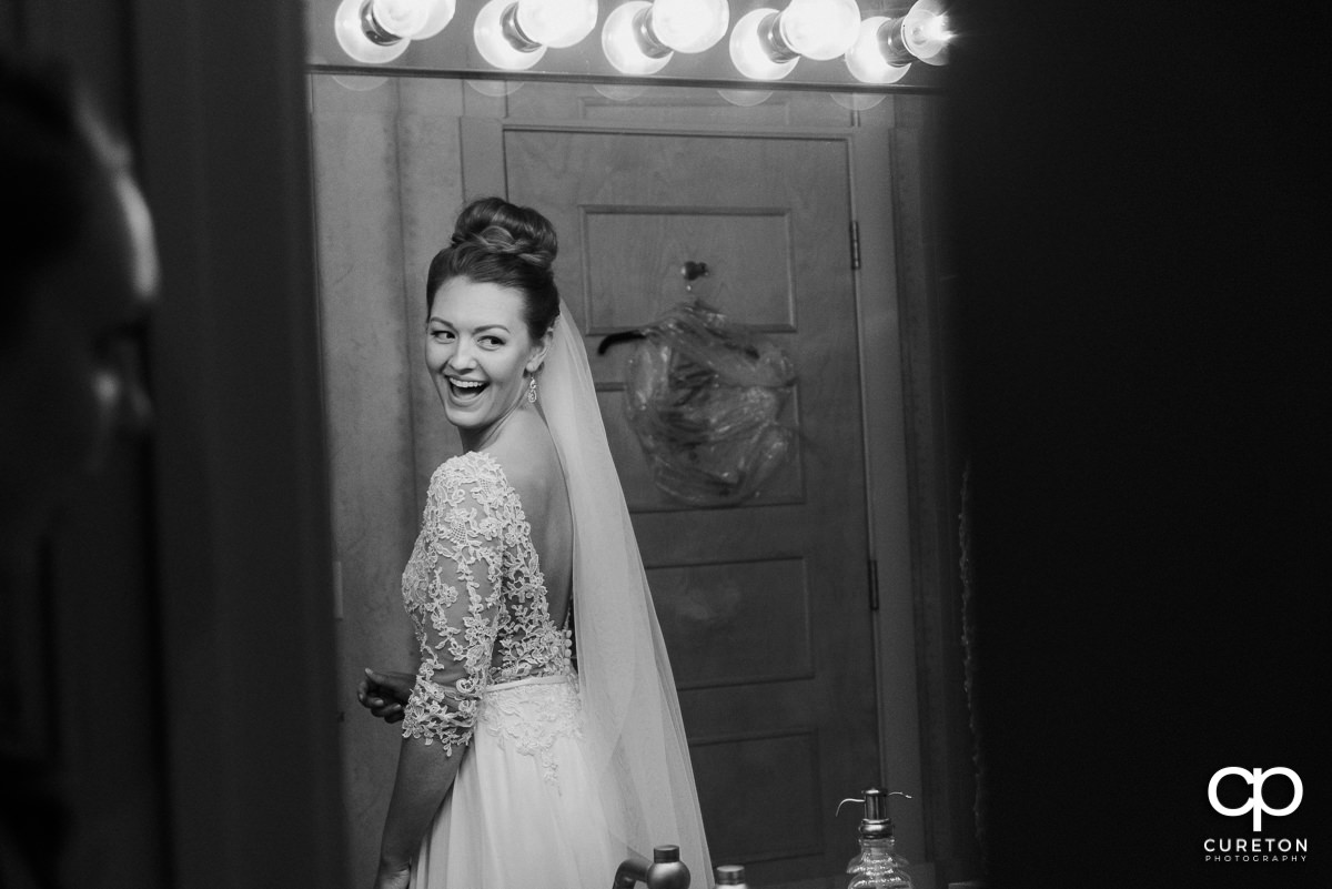 Bride smiling in the mirror as she is getting ready at Soby's Loft in Greenville,SC before the wedding.