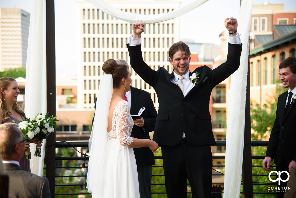 Groom cheering after they are pronounced husband and wife at the rooftop wedding at Soby's Loft in Greenville.