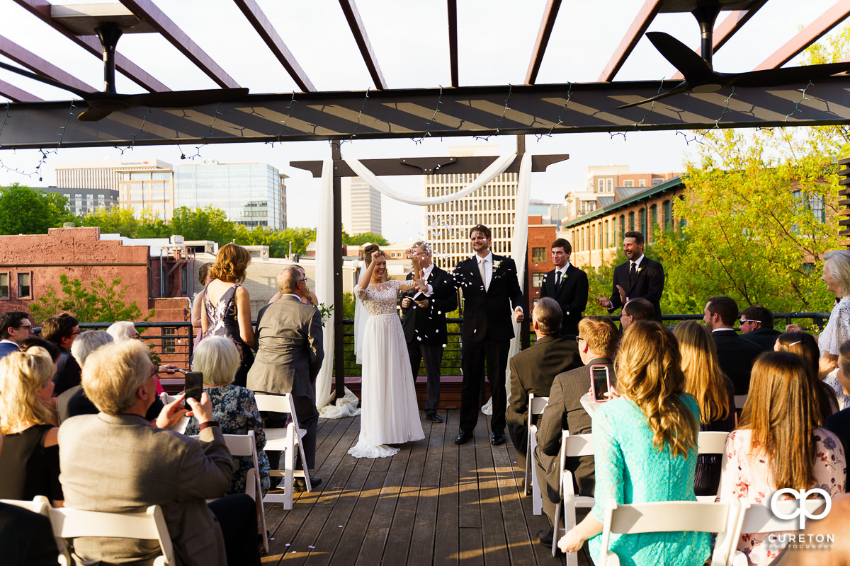 Guests throwing confetti as the newly married husband and wife are walking back down the aisle.