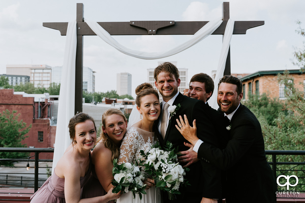 Bridal party hugging the bride and groom on a rooftop after the Soby's Loft wedding.