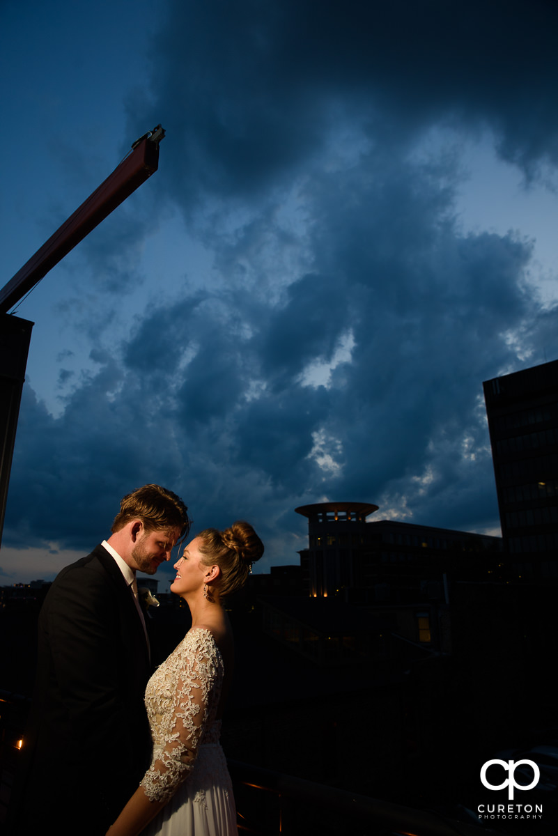 Bride and groom snuggling at sunset on a rooftop during their Loft at Soby's wedding in downtown Greenville,SC.