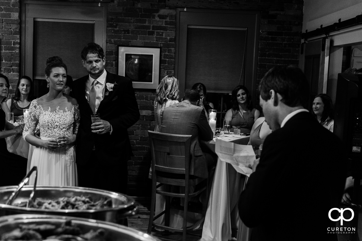 Bride and groom watching the groomsmen give a speech.