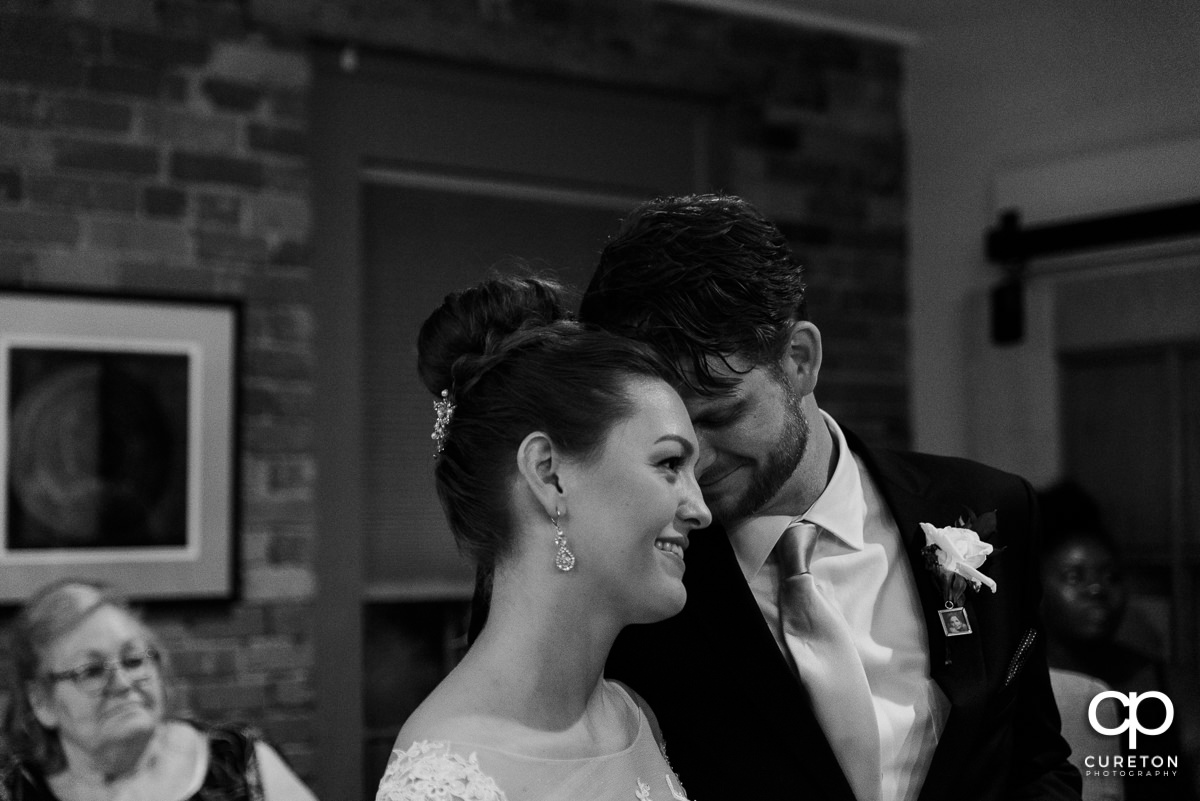 Groom and bride hugging during a speech at the reception.