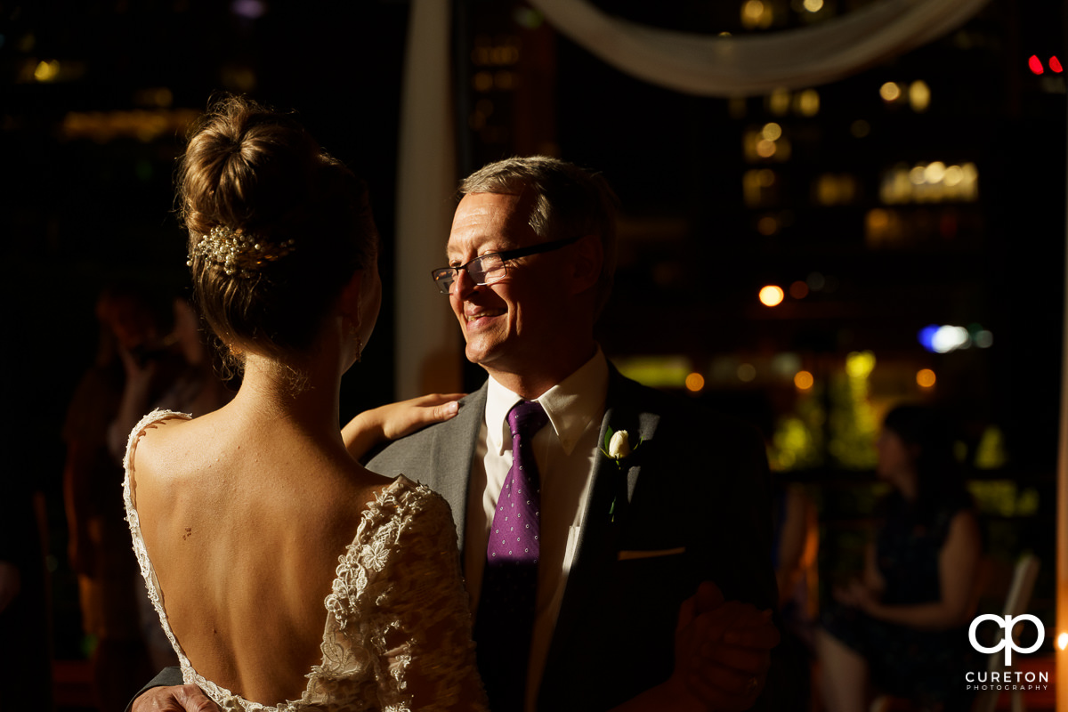 Bride's father smiling as he dances with his daughter at her wedding reception.