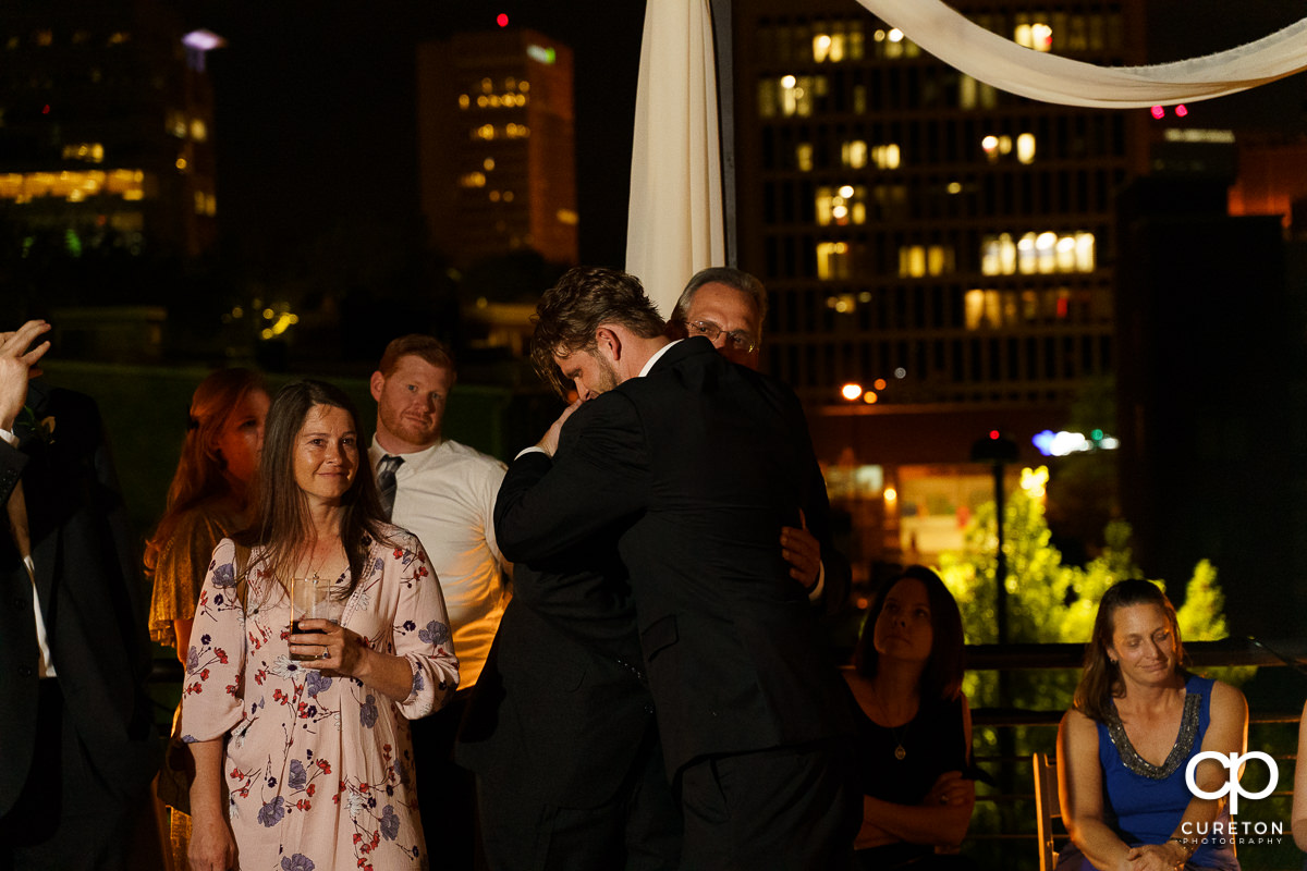 Groom hugging his father at his wedding reception.