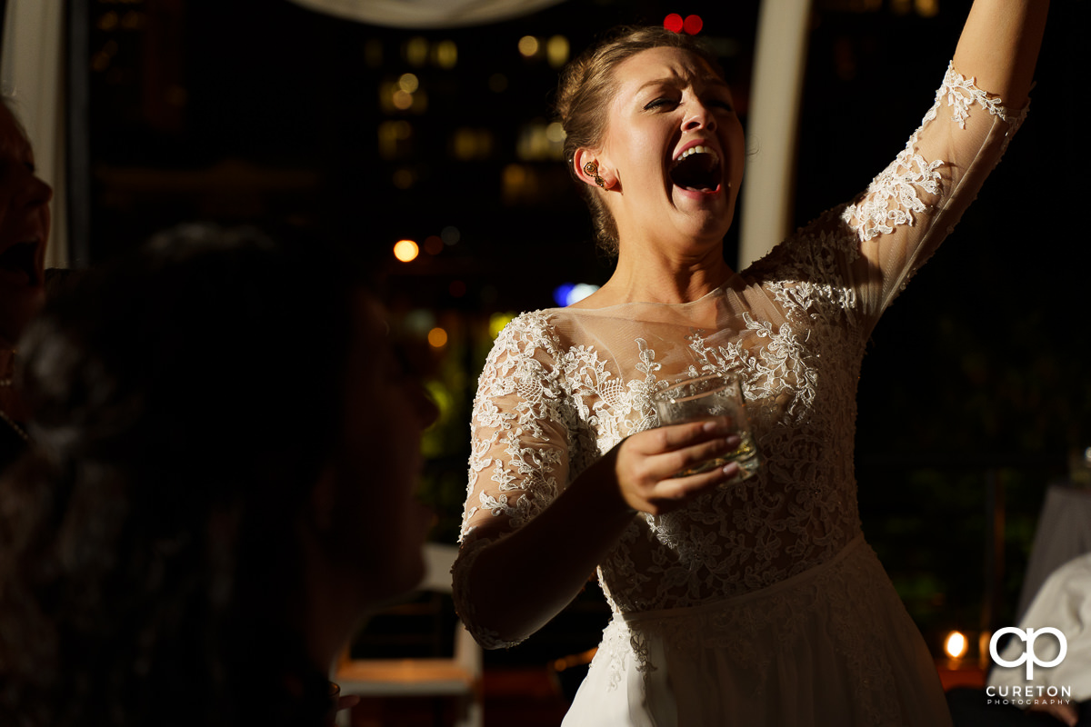 Bride screaming and dancing at the wedding reception on the rooftop at Soby's Loft in Greenville,SC.