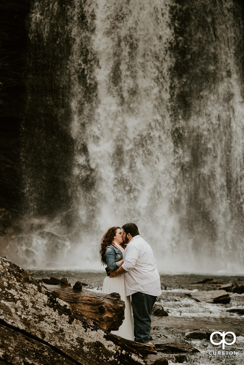 Bride and Groom kissing near a waterfall during their Looking Glass Falls engagement session.