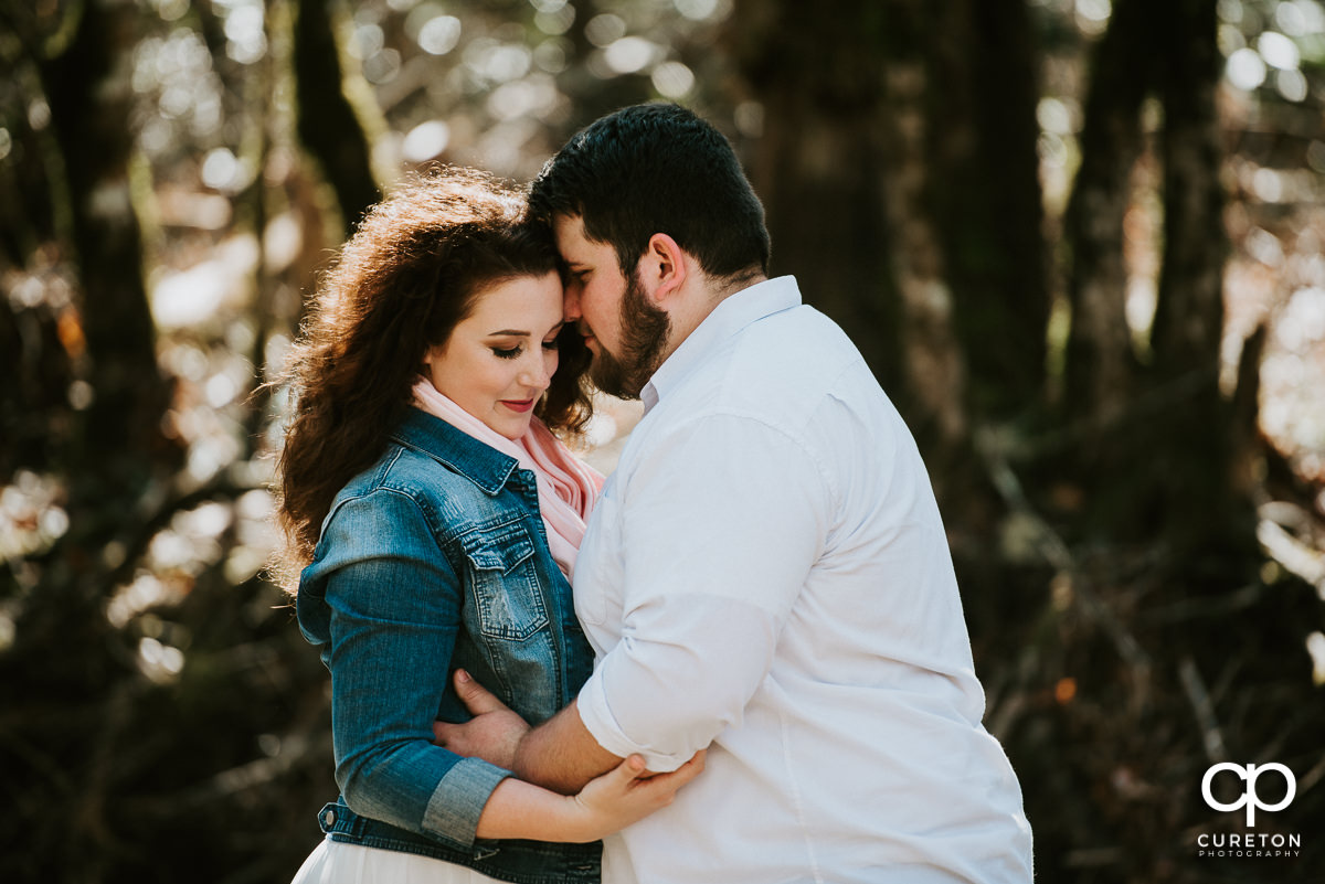 Future bride and groom hugging during an engagement session in Pisgah Forest.