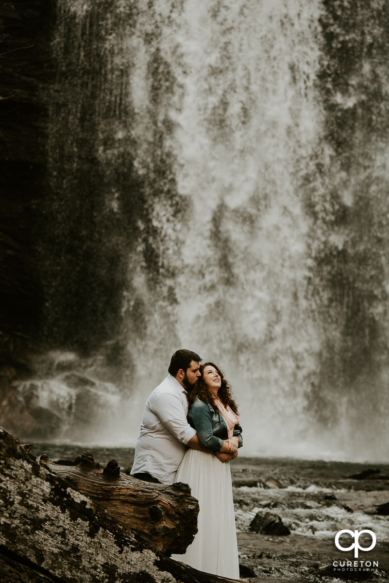 Groom holing his bride and dancing in the water at Looking Glass Falls just minutes from Brevard,NC.