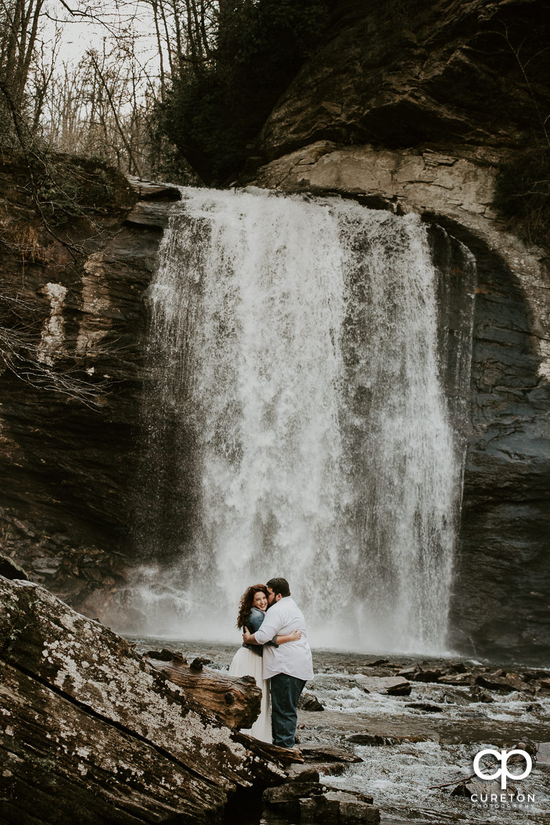 Happy couple dancing in the river in front of a waterfall in the Pisgah Forest.