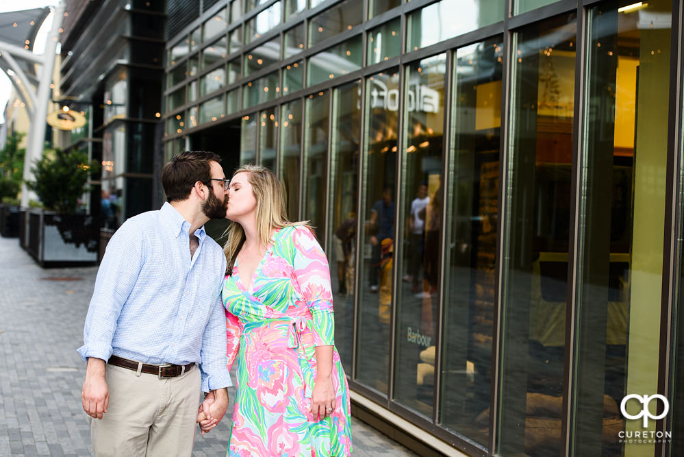 Engaged couple kissing during a Main Street Greenville SC engagement session.