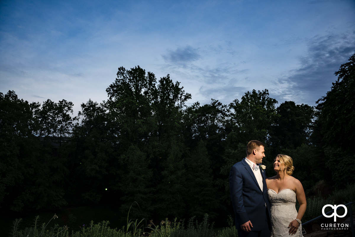 Bride and groom smiling at each other at sunset during their Mary's at Falls Cottage wedding in downtown Greenville,SC.
