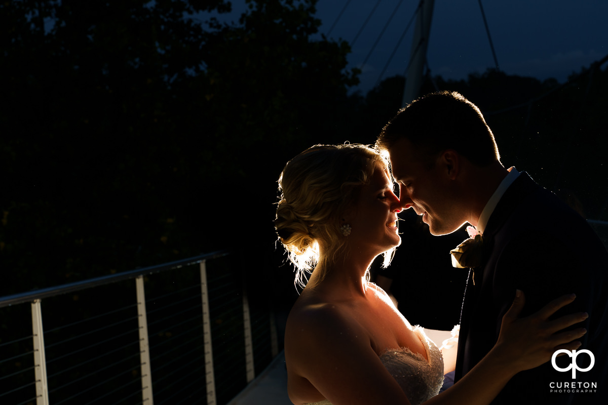 Bride and groom sharing a moment on the Liberty Bridge at night after their Mary's at Falls Cottage wedding in downtown Greenville,SC.