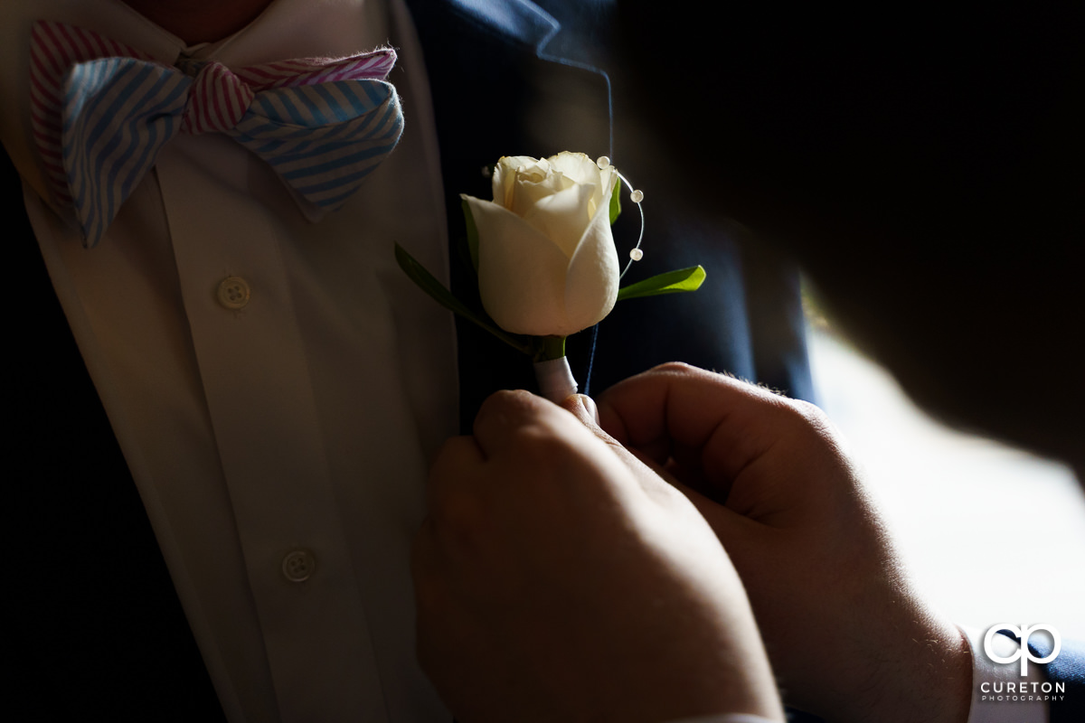 Groom having his boutonniere pinned.