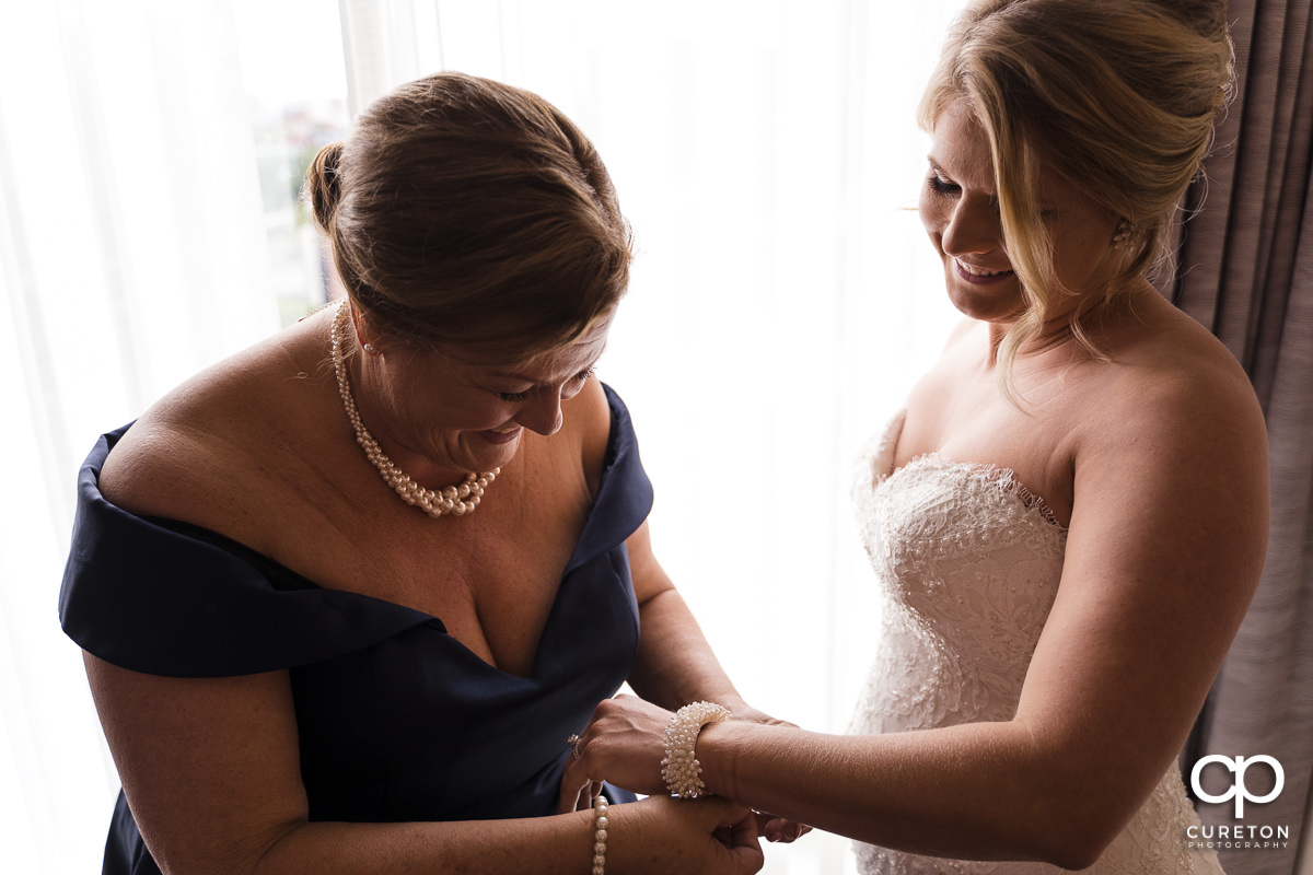 Bride's mother helping her put on a bracelet.
