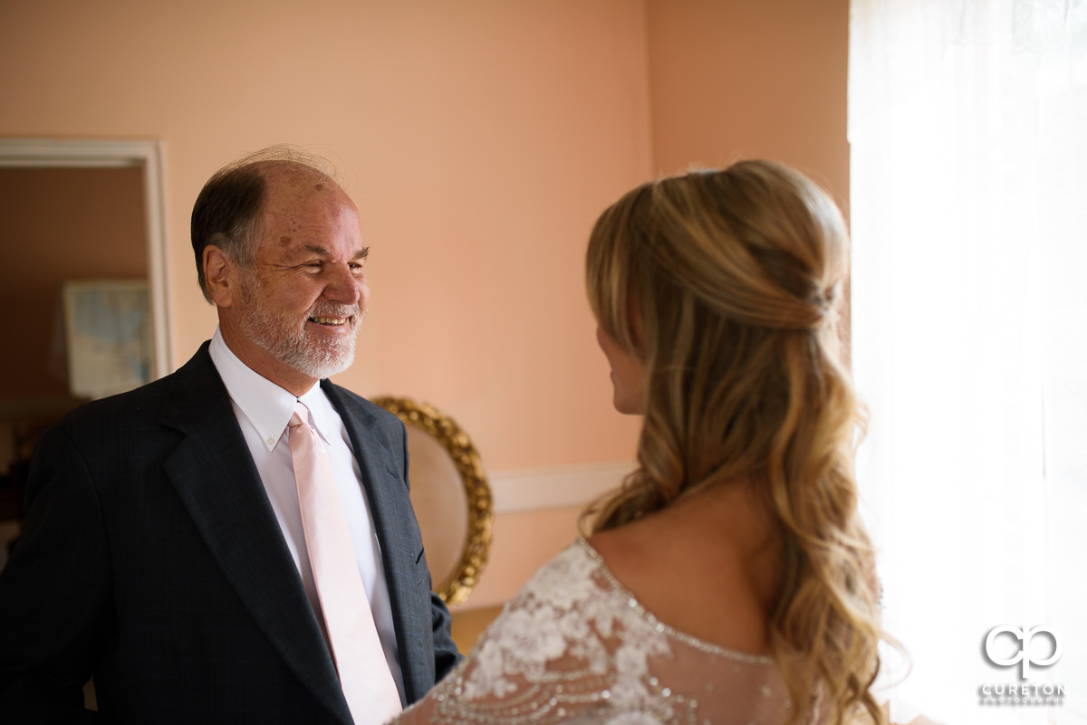 Father of the bride smiling as he sees his daughter in her dress for the first time.