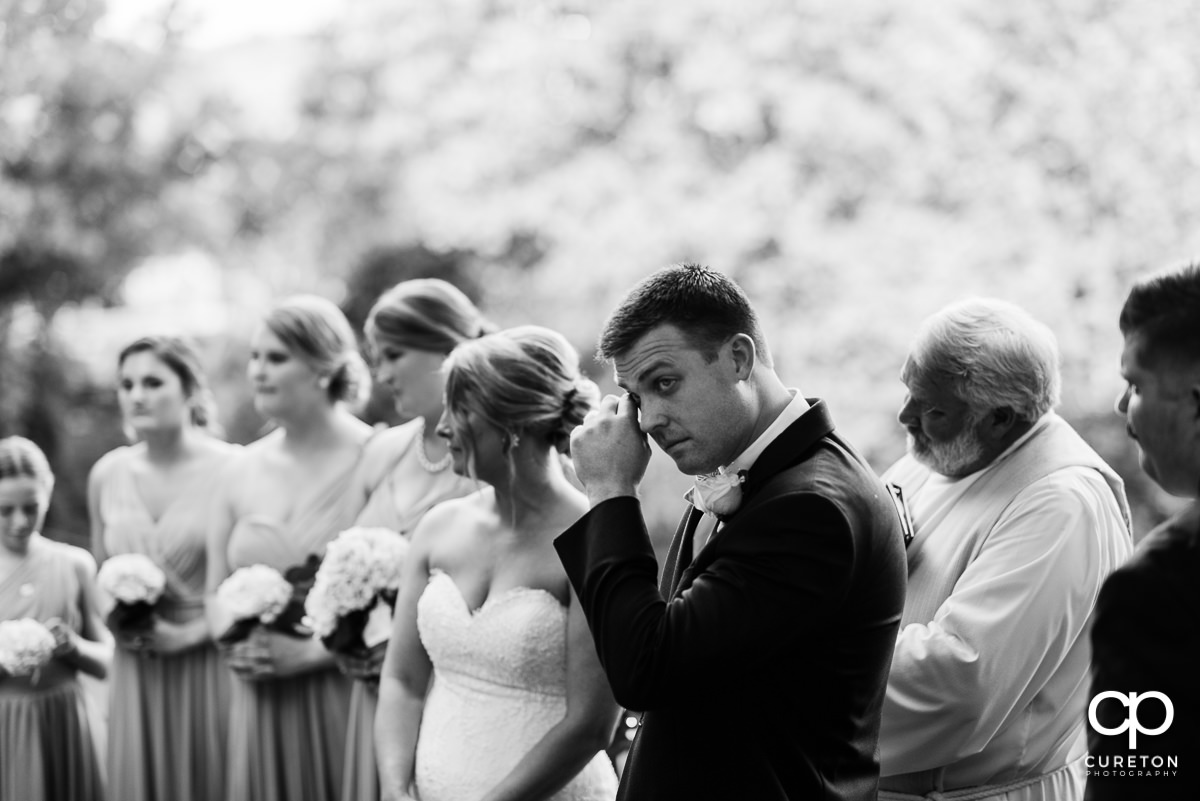 Groom wiping away tears at the wedding ceremony.