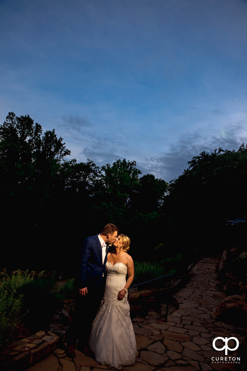 Bride and groom kissing in Falls Park at sunset.