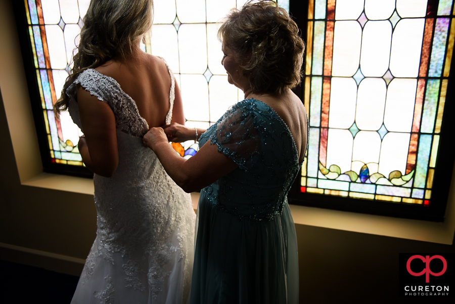 Bride's mom helping her into the dress.