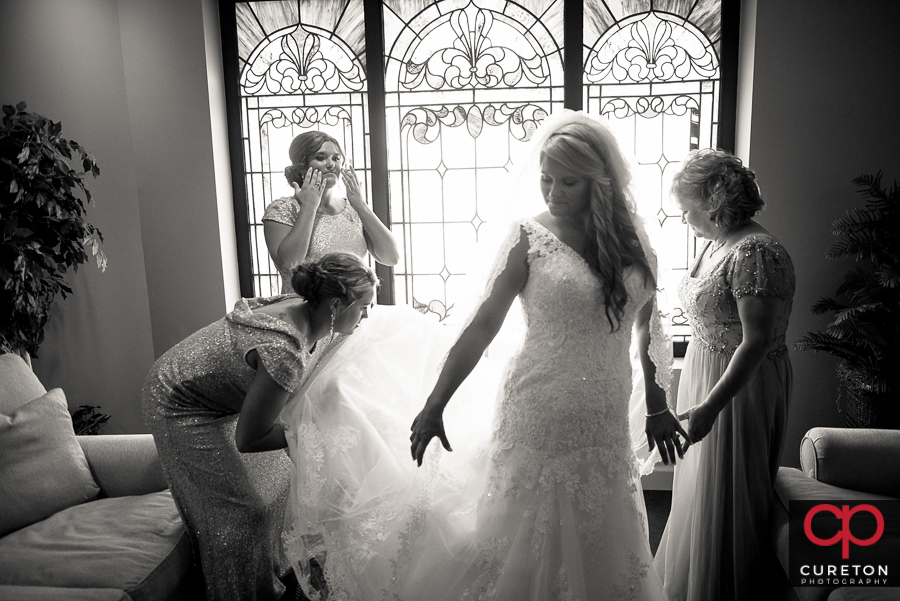 Bride's mom and sisters help her get ready.