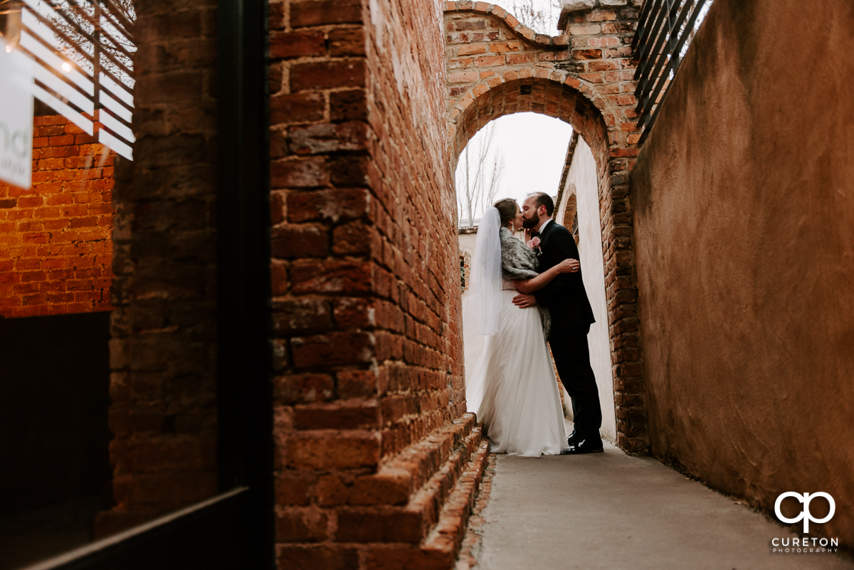 Groom kissing his bride outside of the Old Cigar Warehouse.