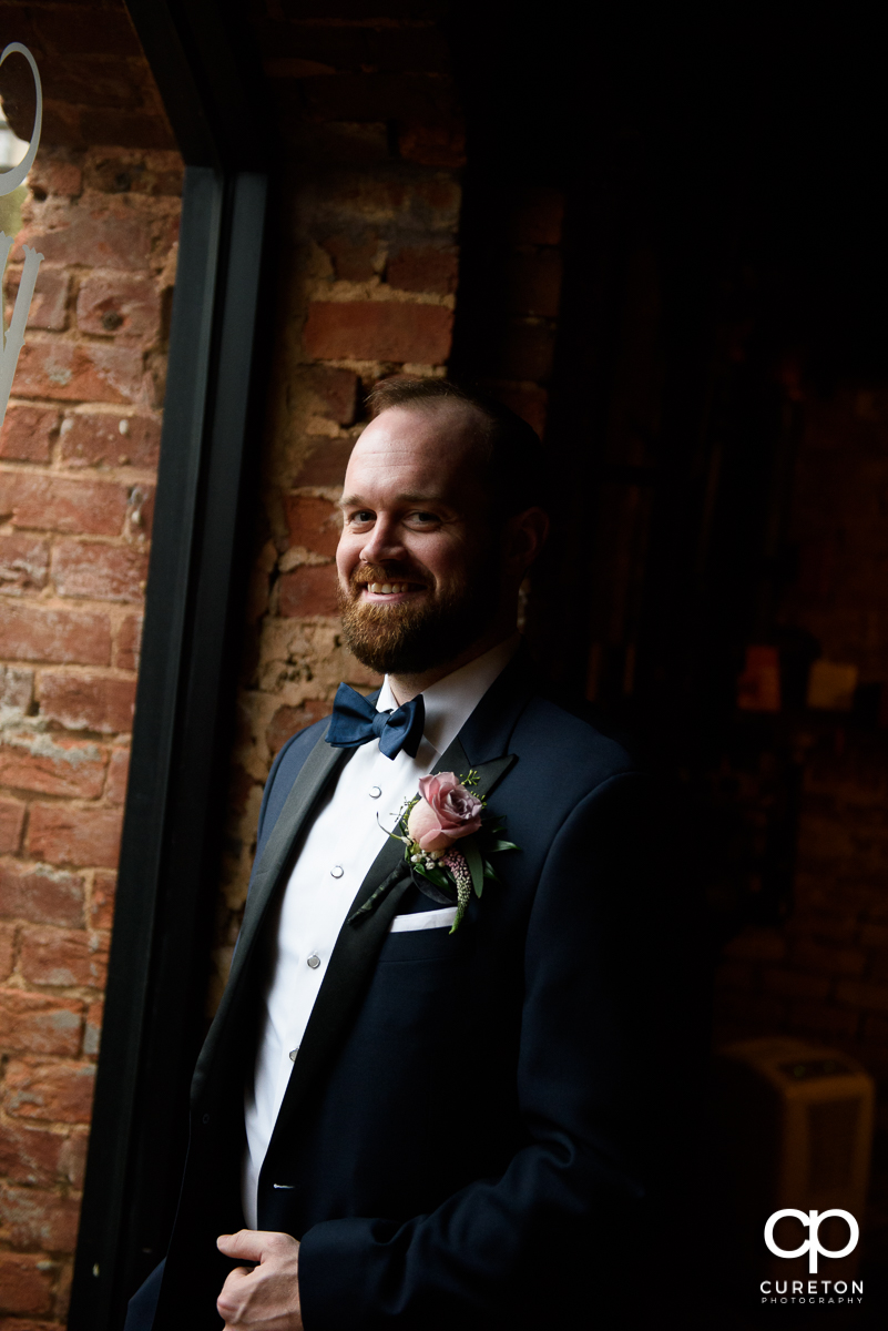 Groom smiling in the window before the ceremony.