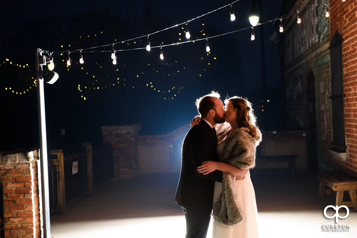 Bride and groom dancing underneath twinkly lights on the deck of the old cigar warehouse.