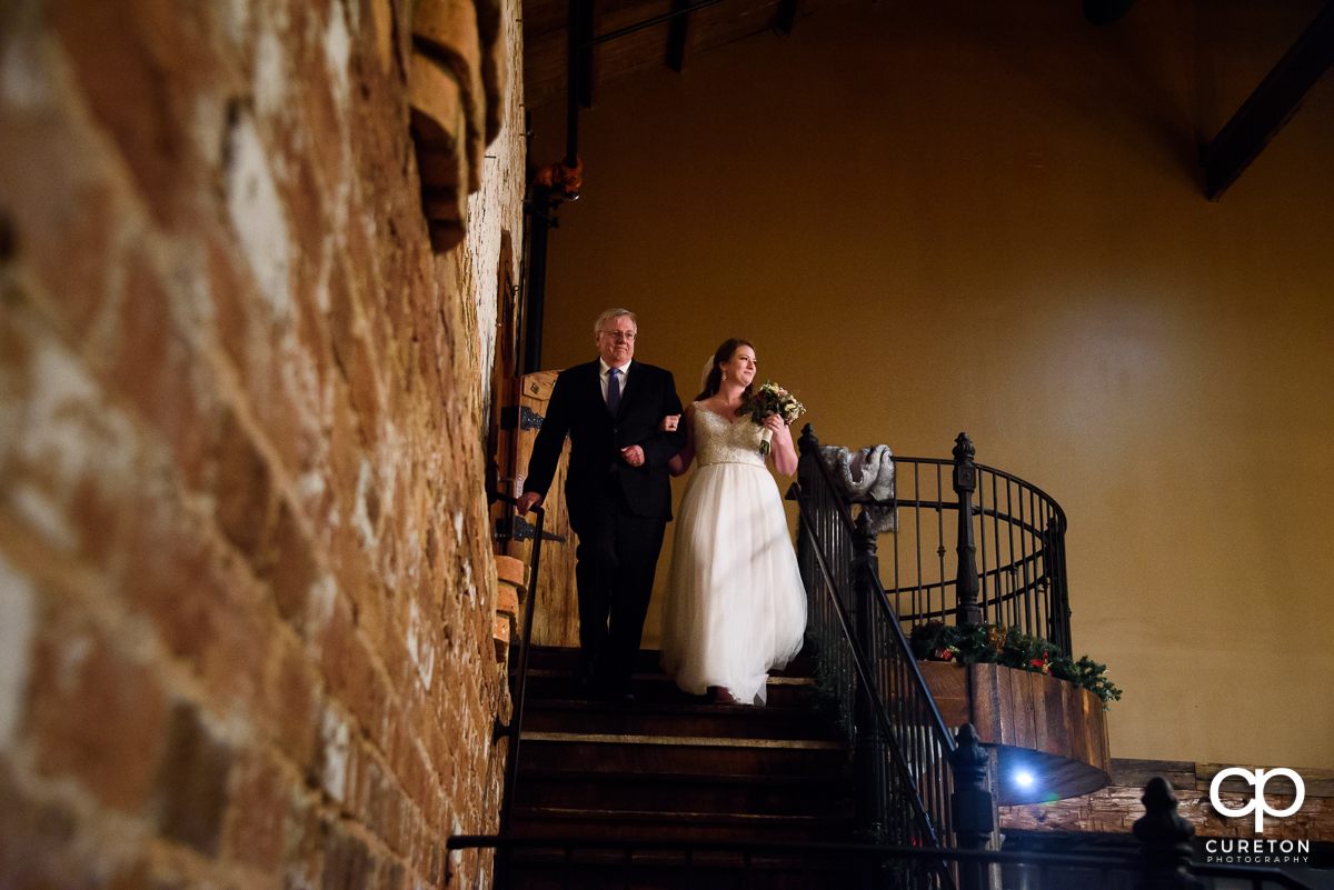 Bride and her father walking down the staircase at their wedding.