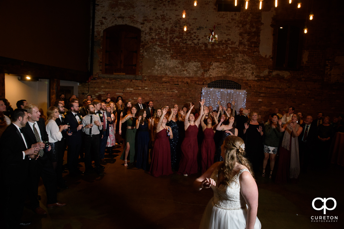 Bride tossing her bouquet at The Old Cigar Warehouse wedding reception.