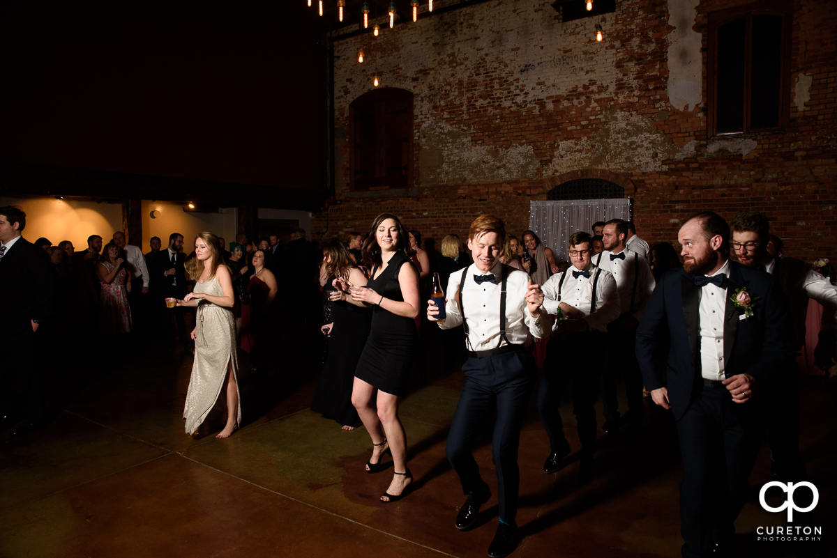 Wedding guests line dancing.