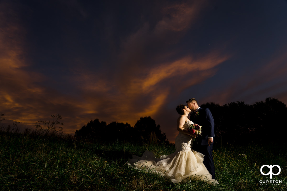 Bride and groom kissing at sunset after their Noah's Event Venue wedding.
