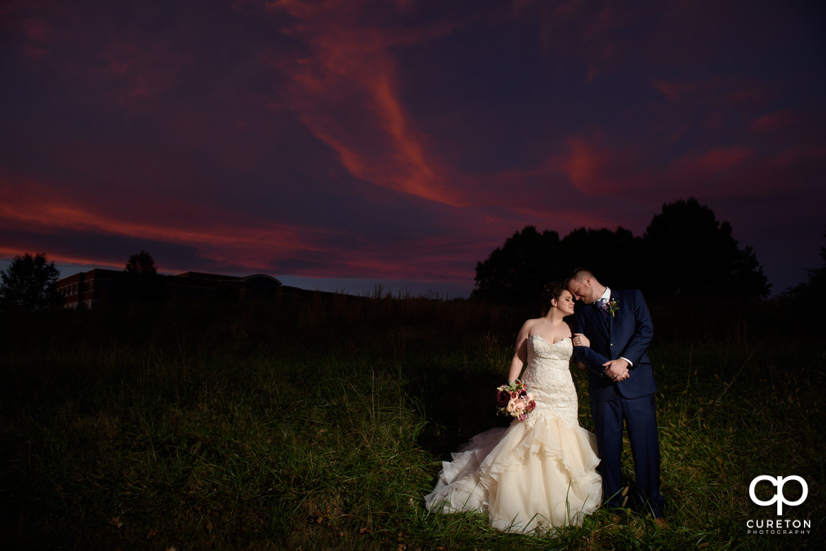 Bride and groom leaning on each other at sunset.