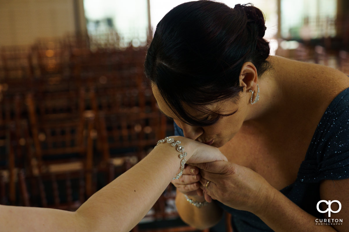 Bride's mother kissing her on the hand.