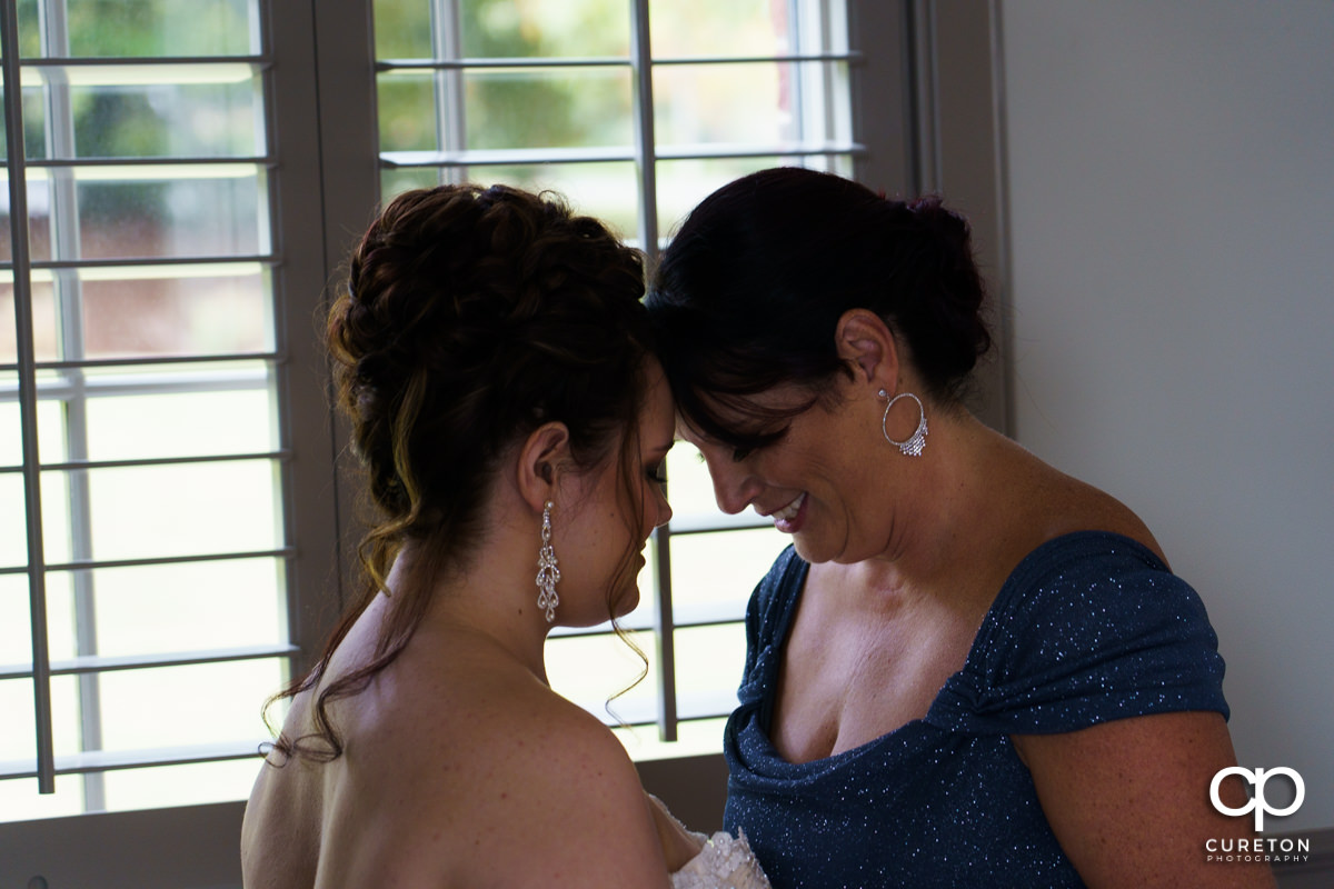 Bride and her mom sharing a moment before her wedding ceremony.