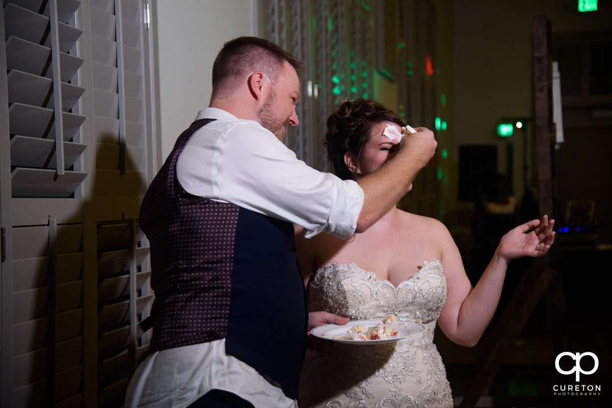 Groom smashing cake on the bride's face.