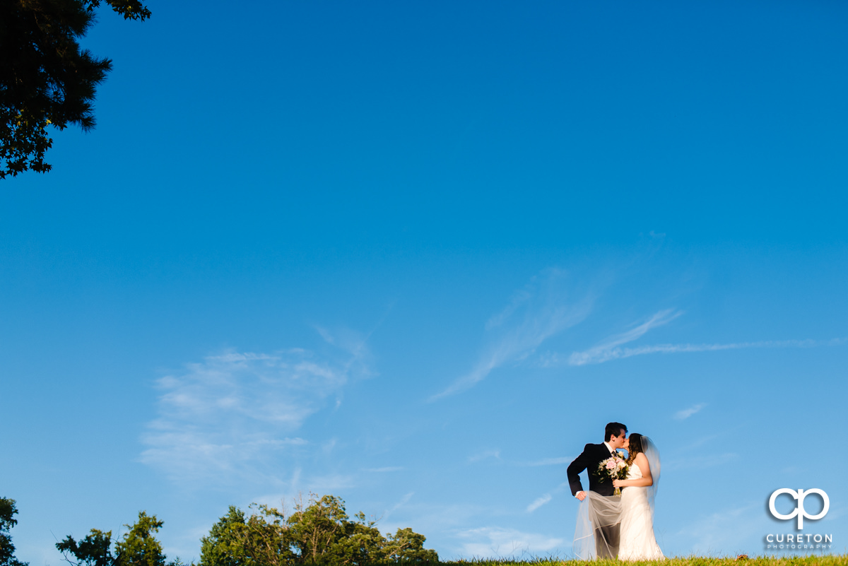 Groom kissing his bride on a hillside at Noah's Event Venue in Greenville,SC.